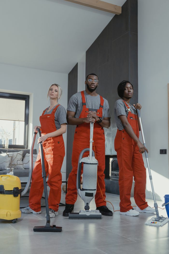 Three uniformed cleaners holding equipment in a contemporary home interior, highlighting teamwork and professionalism.