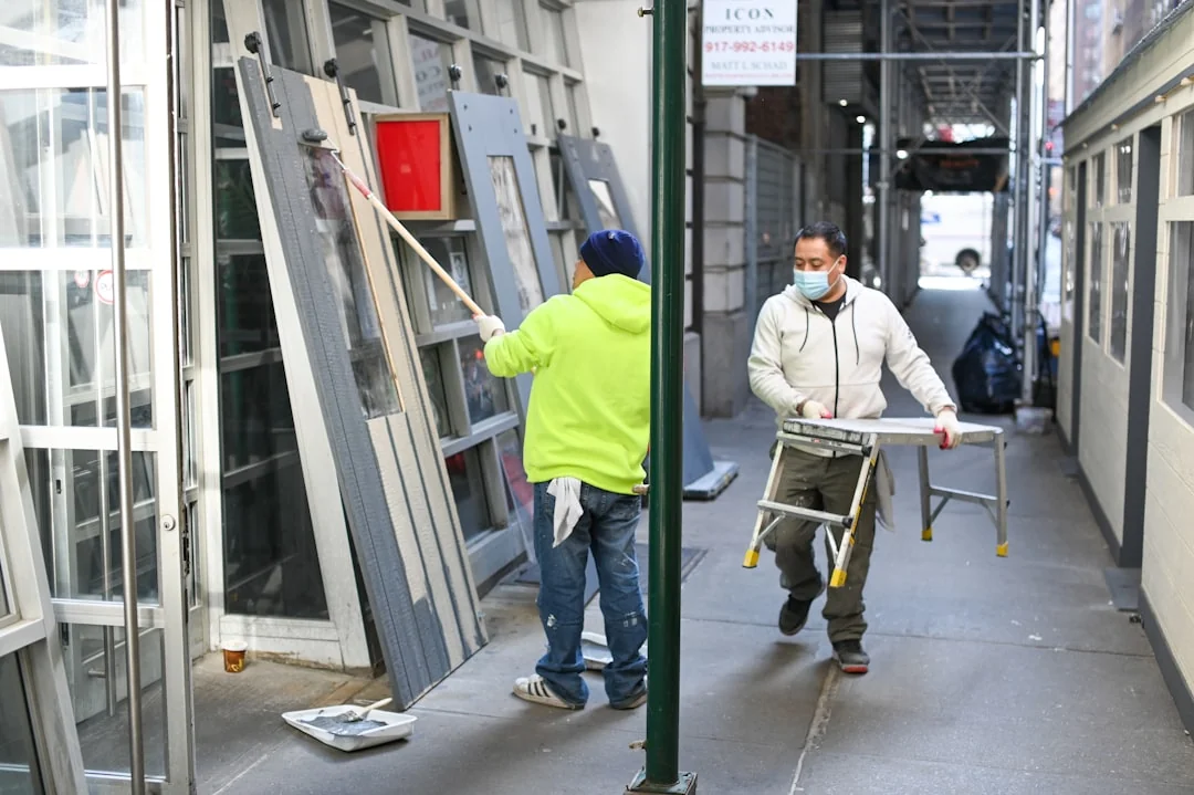Cleaning crew in red uniforms with equipment approaching a modern house exterior.
